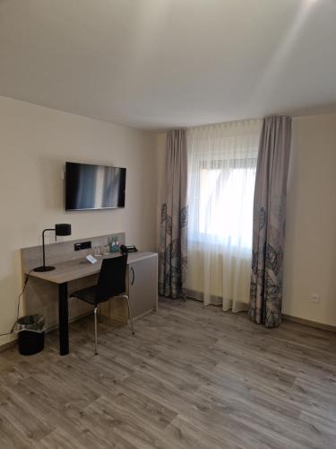a room with a desk and a television and a window at Hotel Alte Bäckerei in Nidderau