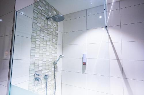 a bathroom with a shower with a glass door at Puzzle Hotel Airport Frankfurt in Rüsselsheim
