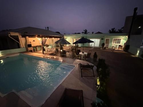 a swimming pool with tables and umbrellas at night at 02 -CASA Praia PINHEIRA in Palhoça