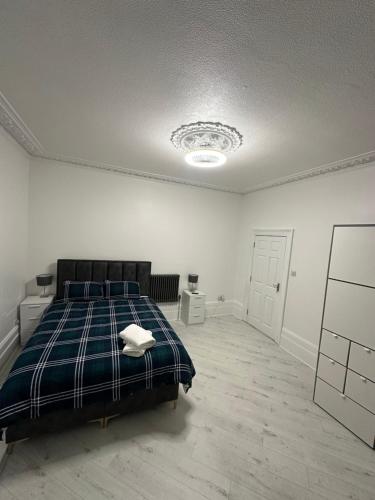 a bedroom with a bed with a blue plaid blanket at Parchmore House in Thornton Heath