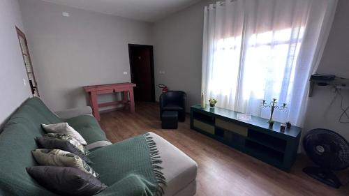 a living room with a green couch and a window at Villa do Aconchego · Próxima ao centro São João da Boa Vista · Casa inteira in São João da Boa Vista