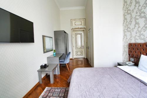 a bedroom with a bed and a desk and a television at Pilot By Haz Hotel in Baku