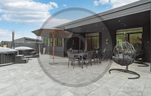 un patio avec une table, des chaises et un parasol dans l'établissement 6 Bedroom Awesome Home In Glesborg, à Fjellerup Strand