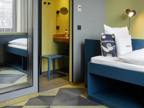 une petite chambre avec un lit et un miroir dans l'établissement 25hours Hotel The Trip, à Francfort-sur-le-Main