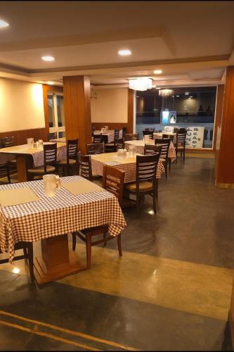Un comedor con mesas y sillas y un restaurante. en The Majestic Crown, en Ooty