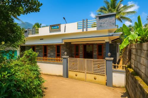 a house with a fence in front of it at Tranquil Gudalur Stay Surrounded by Tea & Forests in Gūdalūr