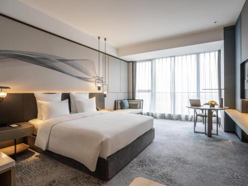 a hotel room with a bed and a desk at Pullman Jiaxing Pinghu Excellence in Jiaxing