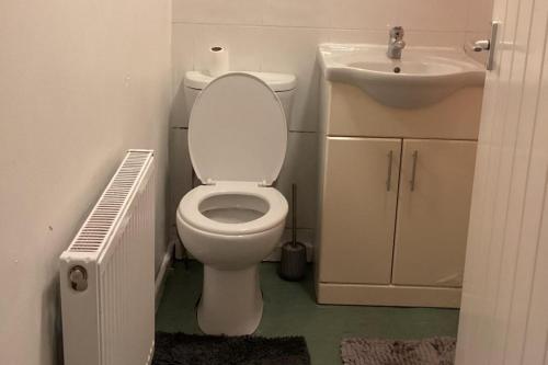 a bathroom with a white toilet and a sink at Sleeps 11 -Pets Ok - Private Garden - Free Parking in Dagenham Dock