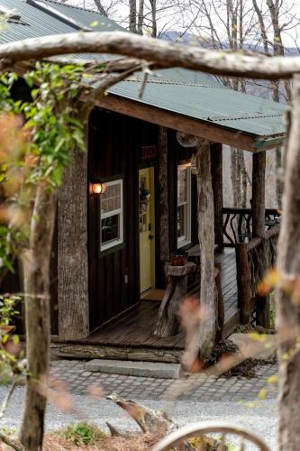Indian Lake EstatesにあるSecluded Delight: Unplug and Reconnect in a Special House in Lake Toxaway's Woodsの黄色いドアが付いた木製のポーチのある小さな家
