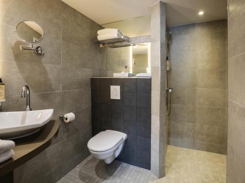 a bathroom with a toilet and a sink and a shower at Mercure Belfort Centre in Belfort