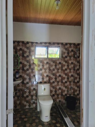 a bathroom with a toilet and a window on the wall at Siargao Villaflor Residence in Dapa