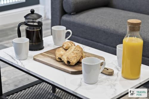 a coffee table with a tray of cookies and a bottle of orange juice at Bella's House 12mins bus to Motor Point Arena Free Street Parking in Nottingham