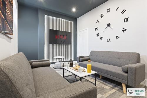 a living room with a couch and a clock on the wall at Bella's House 12mins bus to Motor Point Arena Free Street Parking in Nottingham