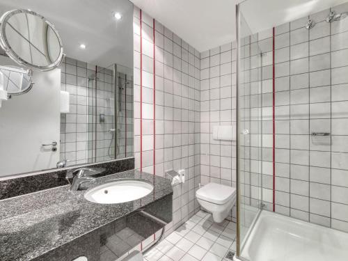 a bathroom with a toilet and a sink and a mirror at Mercure Parkhotel Mönchengladbach in Mönchengladbach