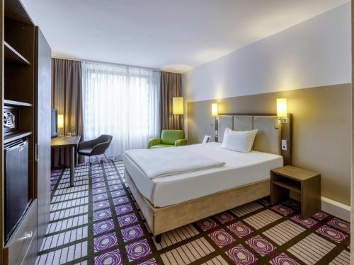 a hotel room with a bed and a desk at Mercure Parkhotel Mönchengladbach in Mönchengladbach