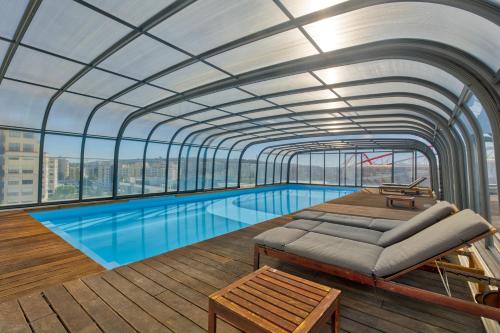 a large swimming pool in a building with a ceiling at Vita Portucale ! Benfica Lux Garden in Lisbon