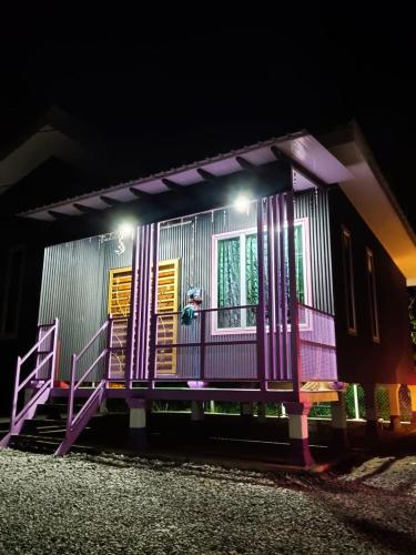 a small house with purple and yellow trim at night at Homestay kak bee d' bendang in Jitra