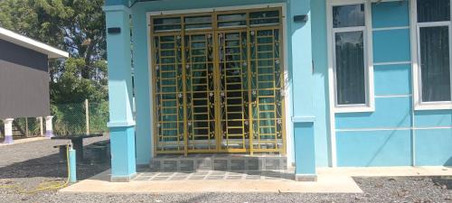 a blue building with a wooden door with a bench at Homestay kak bee d' bendang in Jitra