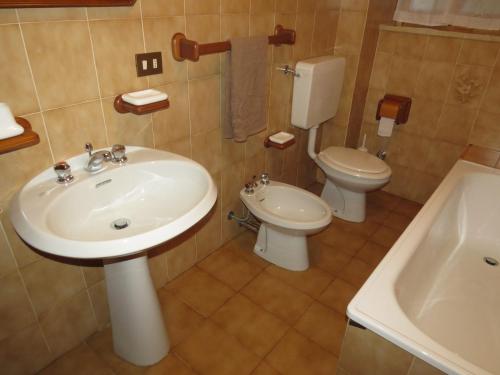 a bathroom with a sink and a toilet and a tub at Baita Sostasio in Prato Carnico