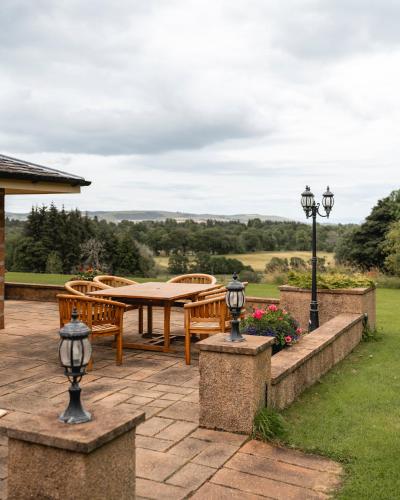 a patio with a table and benches and lights at Balnagown Estates in Kildary