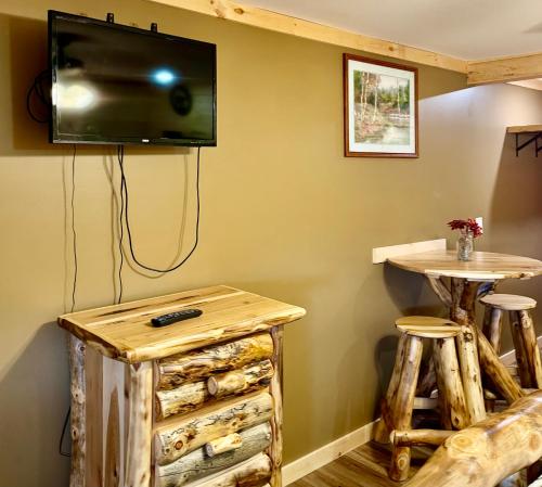 a room with a tv on a wall with a table and stools at The Lake George Inn in Lake George