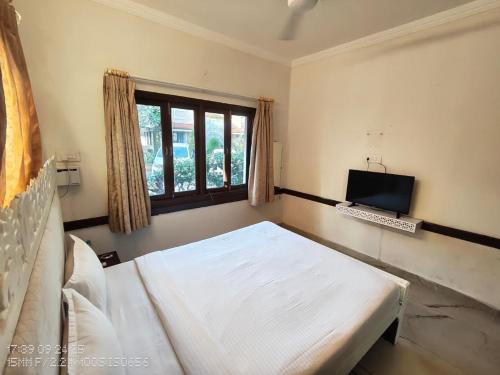 a bedroom with a bed and a window and a computer at Candolim beach apartment goa in Candolim