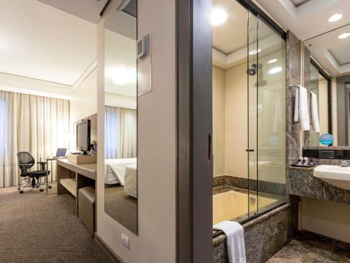 a hotel room with a bathroom with a sink and a shower at Grand Mercure Curitiba Rayon in Curitiba