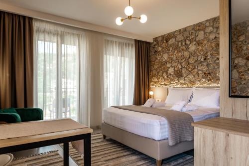 a bedroom with a large bed with a stone wall at Helios Sivota in Sivota