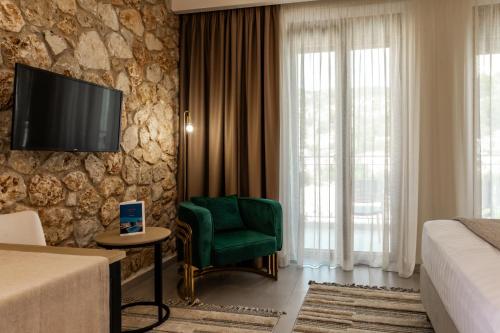 a hotel room with a green chair and a tv on a wall at Helios Sivota in Sivota