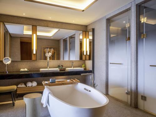 a bathroom with a tub and two sinks and a mirror at Pullman Dali in Dali