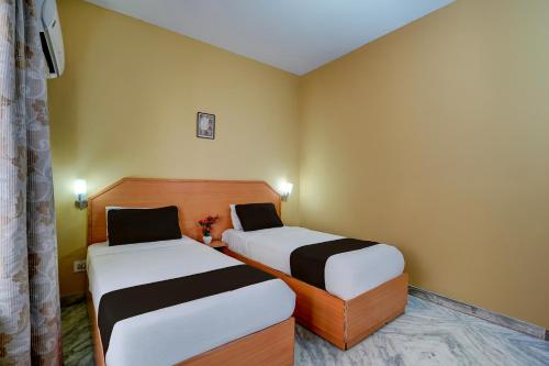 two beds in a room with yellow walls at Hotel O ALT pods in Bengaluru