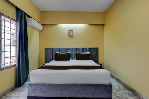 a bedroom with a large bed in a yellow wall at Hotel O ALT pods in Bengaluru