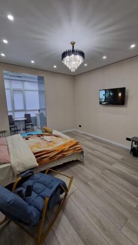 a bedroom with a large bed and a chandelier at Апартаменты в ЖК Атамура in Karagandy