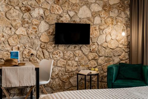 a bedroom with a stone wall with a tv on it at Helios Sivota in Sivota