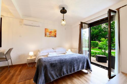 a bedroom with a bed and a sliding glass door at TOMLJANOVIĆ in Plitvička Jezera