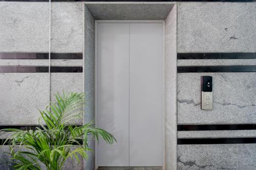 a white door on a concrete wall with plants at Hotel O De' BVL Grand in Hyderabad
