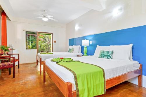 two beds in a bedroom with a blue wall at Coconut Row Boutique Hotel in Hopkins