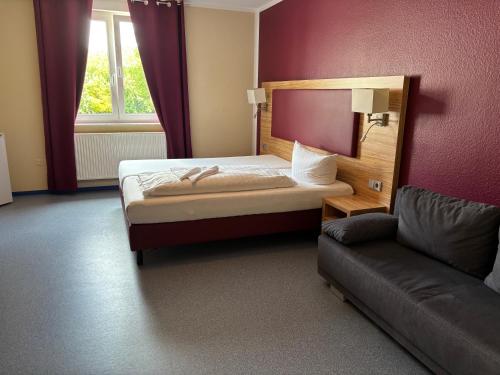 a small bedroom with a bed and a couch at Hotel am Limes in Altenstadt