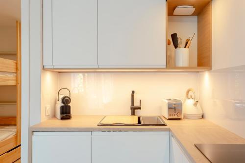 a kitchen with white cabinets and a sink at La Loggia du Triton - Superbe T2 avec parking in Le Grau-du-Roi