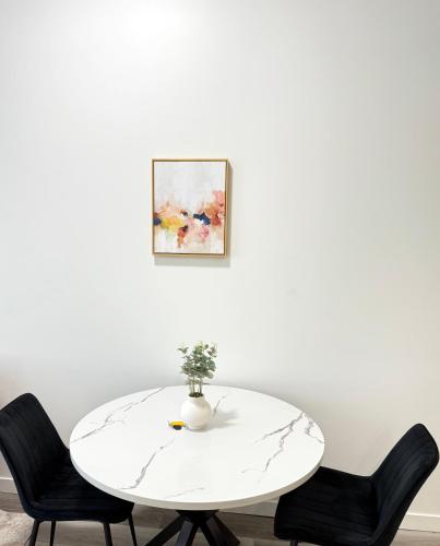 a white table with two chairs and a vase on it at Cozy 1-Bedroom with Downtown City views in Edmonton