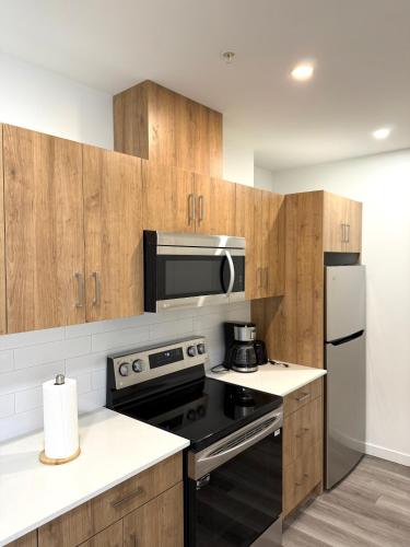a kitchen with wooden cabinets and a stove and refrigerator at Cozy 1-Bedroom with Downtown City views in Edmonton