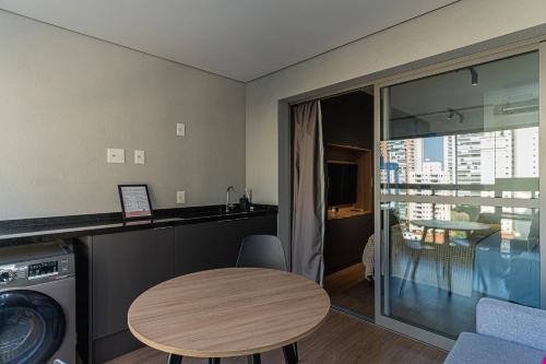 a room with a table and a kitchen with a balcony at Bauhaus Vista 360° - Piscina Rooftop in Sao Paulo