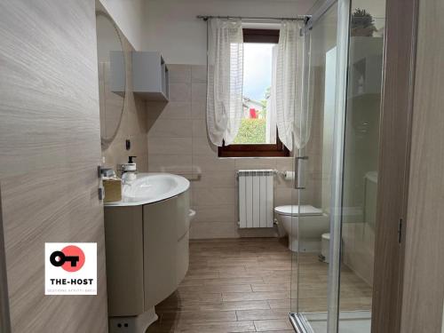 a bathroom with a sink and a toilet and a window at Large apartment with garden and cinema room in Giussano