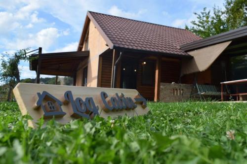 a sign in the grass in front of a house at Log cabin in Sejdanovići
