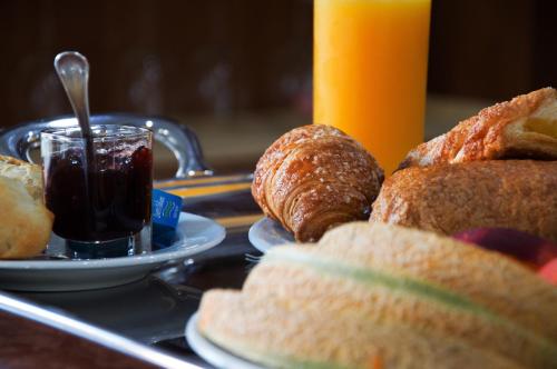 a tray of food with bread and croissants and a drink at Hotel Visconti in Melzo