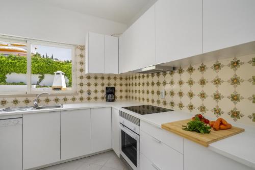 a kitchen with white cabinets and a cutting board at Villa Sitambo- Pool & Sea View in Albufeira