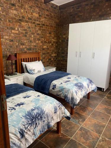 a bedroom with two beds and a brick wall at Come Again Self Catering in George