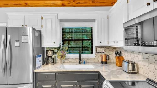 eine Küche mit Kühlschrank und Spüle in der Unterkunft Lakeside Cabin w Hot Tub Fireplace Near Dollywood Trails Smoky Shores Retreat by AvantStay in Little Cove