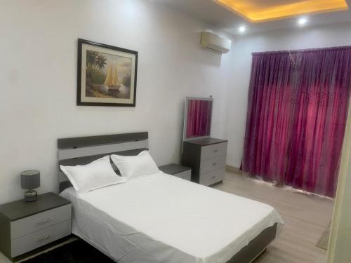 a bedroom with a white bed and purple curtains at Luxurious 3-Bedroom Apartment with a swimming pool in Dakar
