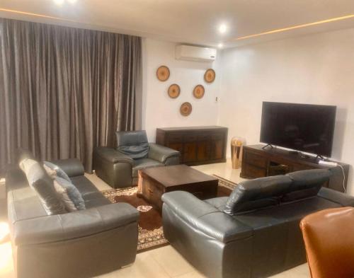 a living room with leather furniture and a flat screen tv at Luxurious 3-Bedroom Apartment with a swimming pool in Dakar